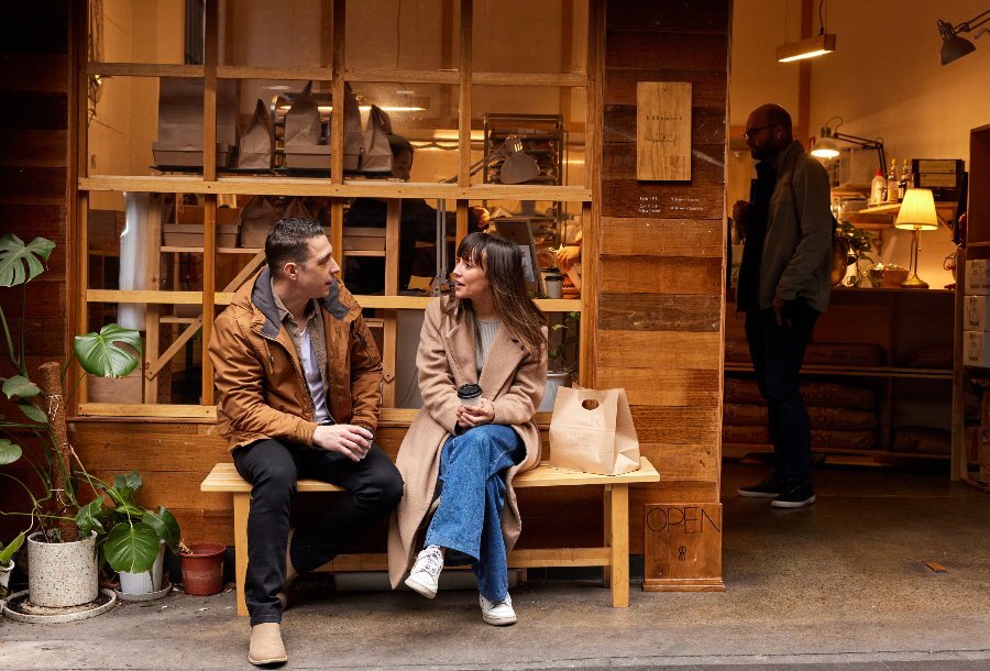 Two people are sitting in front of a small cafe