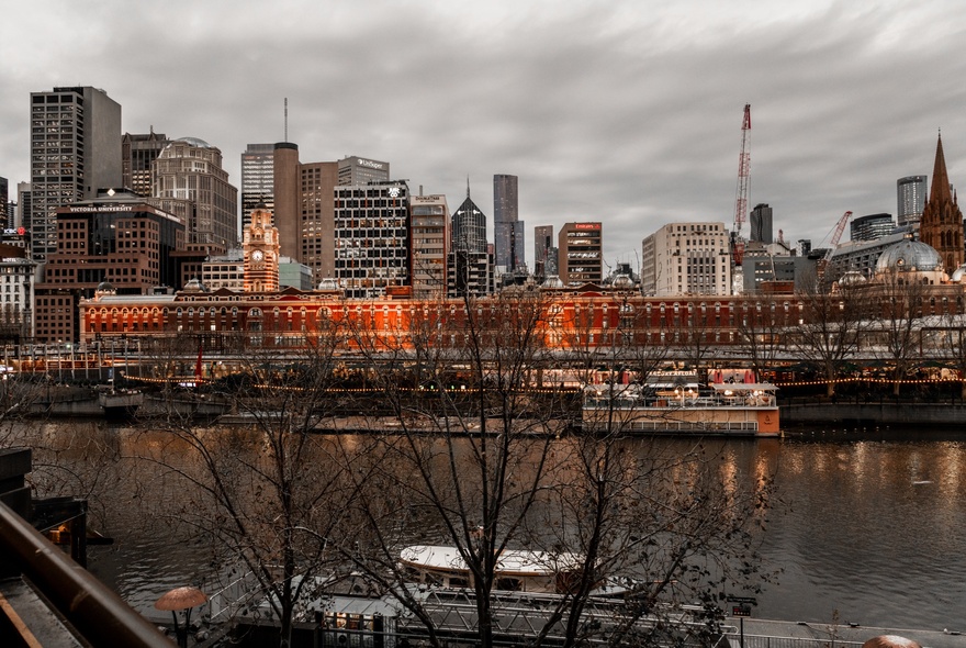A view from the balcony at Commune Wine at dusk of the Yarra River, Flinders Street Railway station and the Melbourne city skyline.