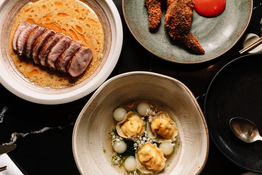 Looking directly down on three plates of restaurant food. 