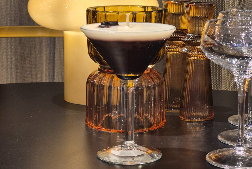 An espresso martini-inspired candle in a martini glass.