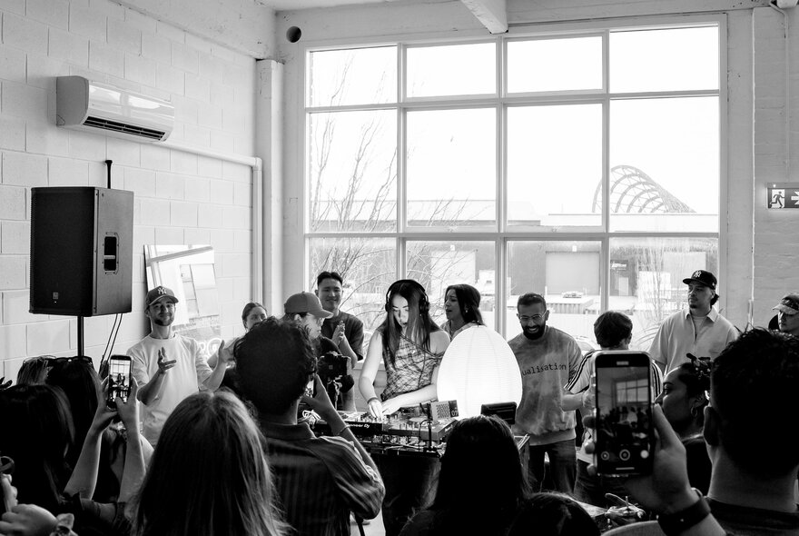 Crowded cafe interior with DJ performing.