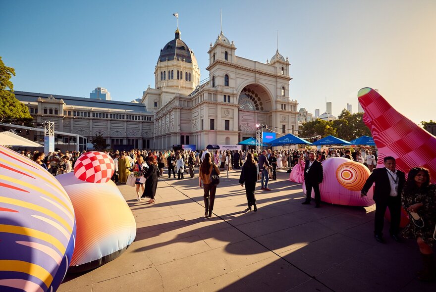 The Fashion Forecourt located outside the Royal Exhibition Building, with people milling around the entrance near large inflatable sculptures.