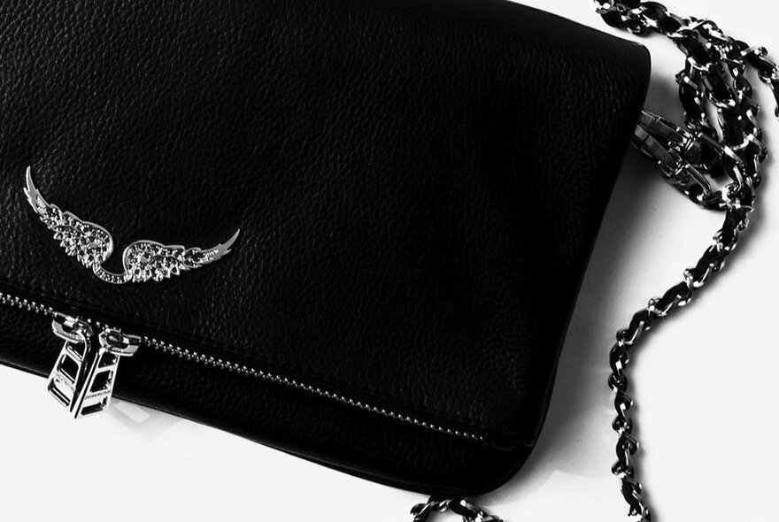 Black handbag with metallic details and strap.