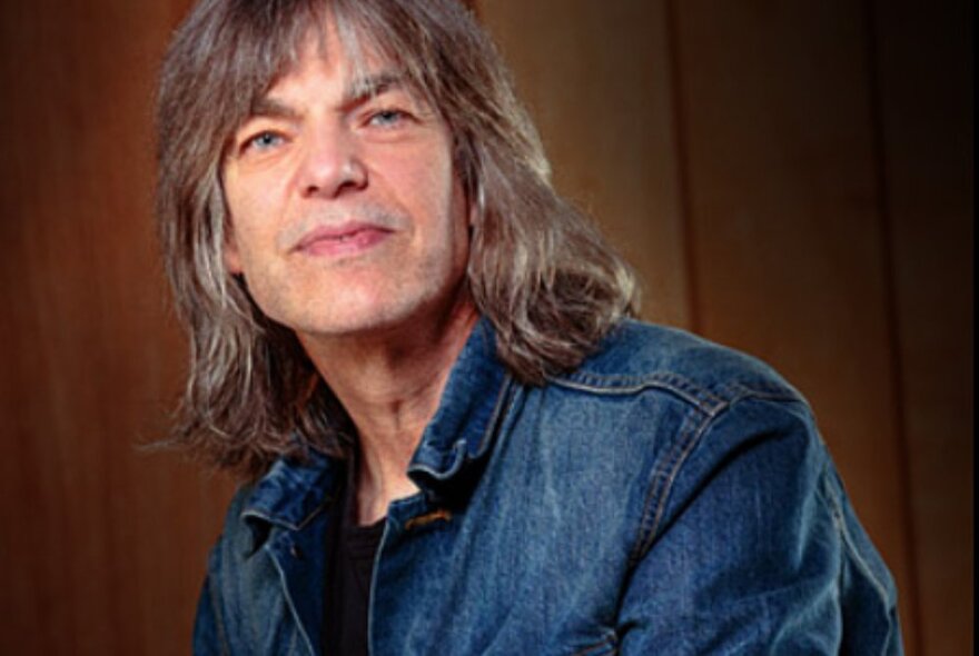 Guitarist Mike Stern with shoulder-length hair and denim jacket.