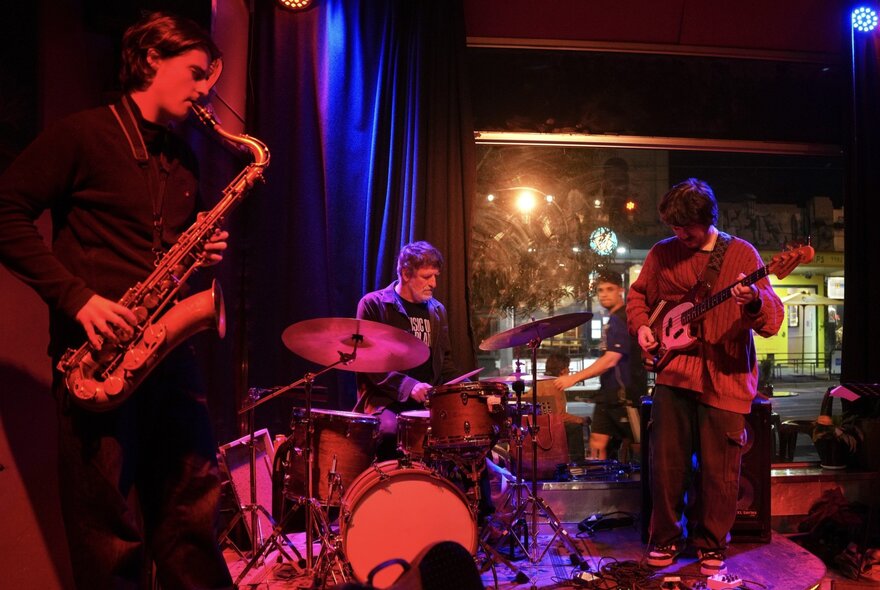Jazz trio performing in a dark club under red and blue lights.