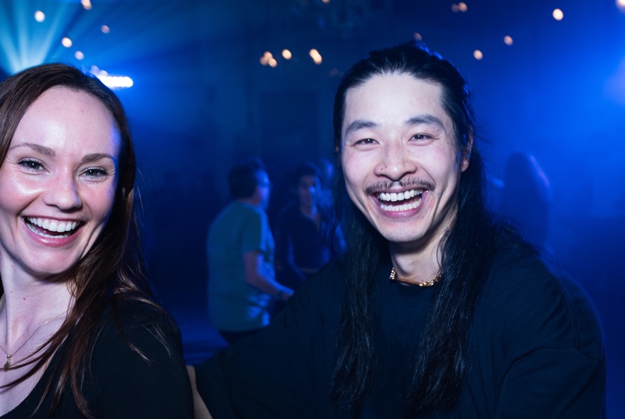 Smiling people on a dance floor with lights.