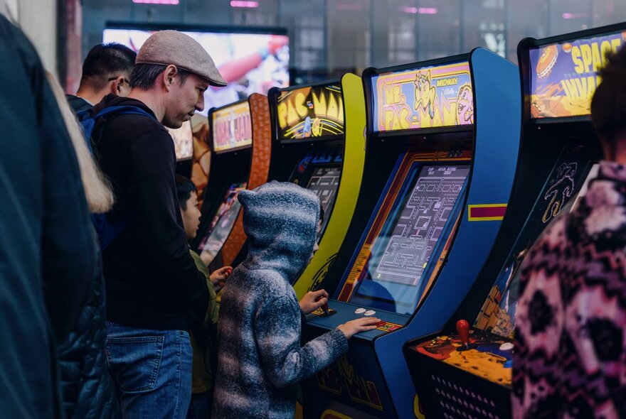 Father and son playing a vintage video arcade game.