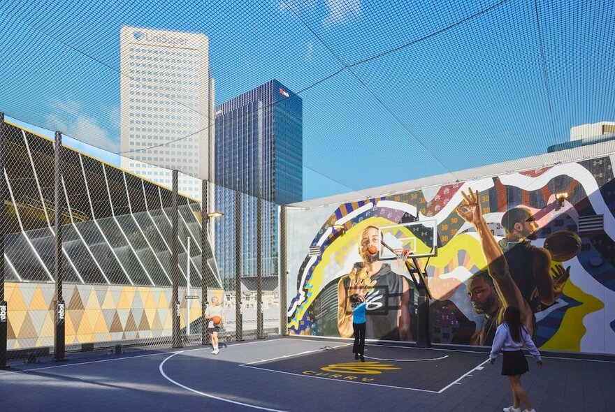 An outdoor basketball court at Rebel Emporium in the Melbourne CBD, with kids playing and large mural. 