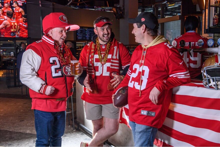Sports fans wearing NFL outfits in a sports-themed bar.