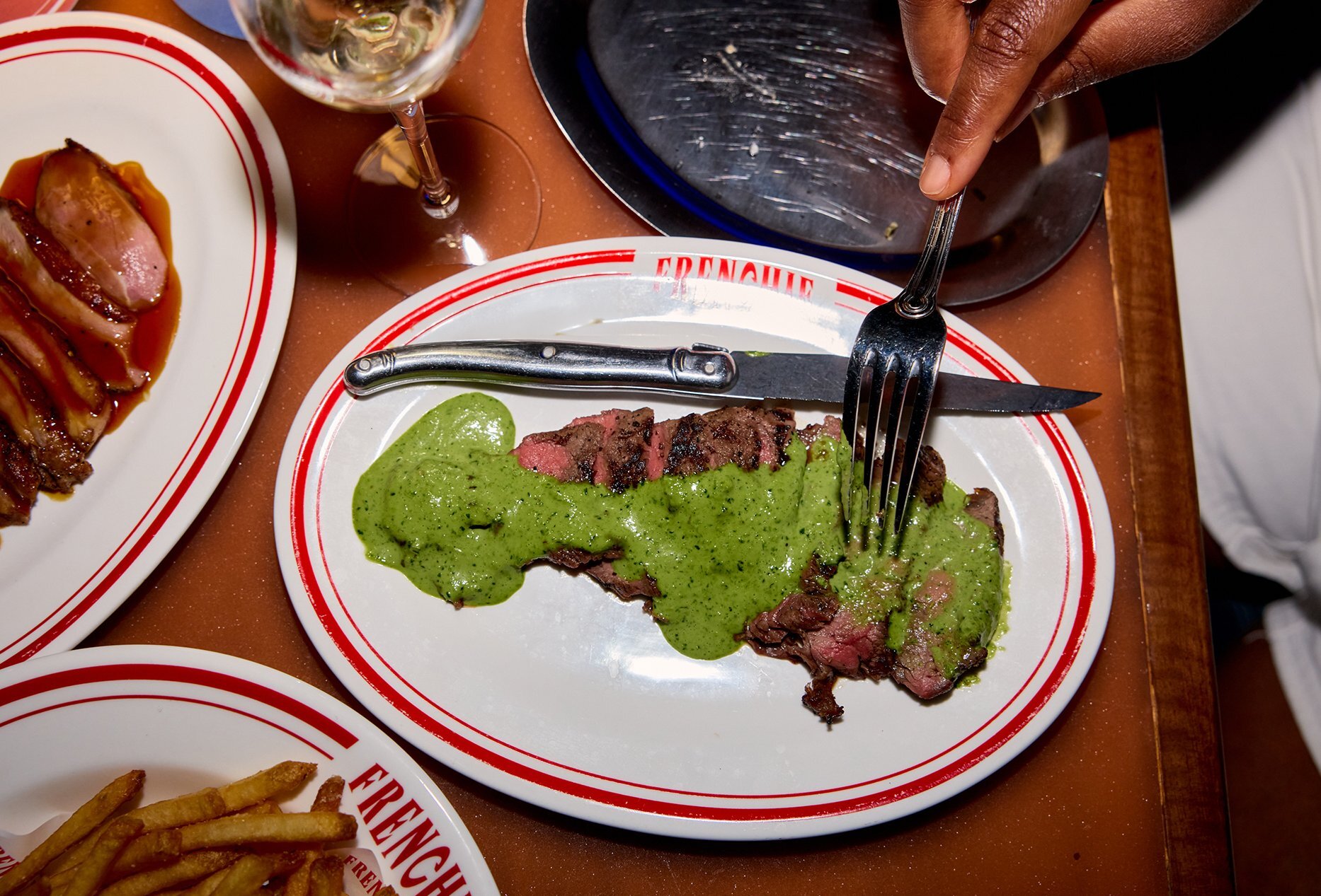 A sliced steak covered in green herb sauce in a restaurant.