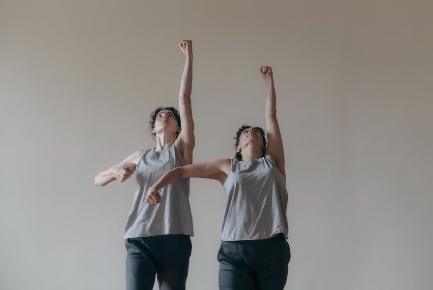 Two dancers performing with arms outstretched to the ceiling.