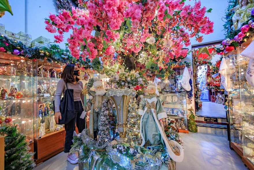 a woman looking at a display of ornaments in a Christmas store