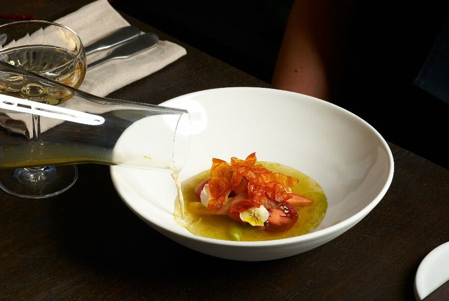 Dressing being poured over a colourful salad.