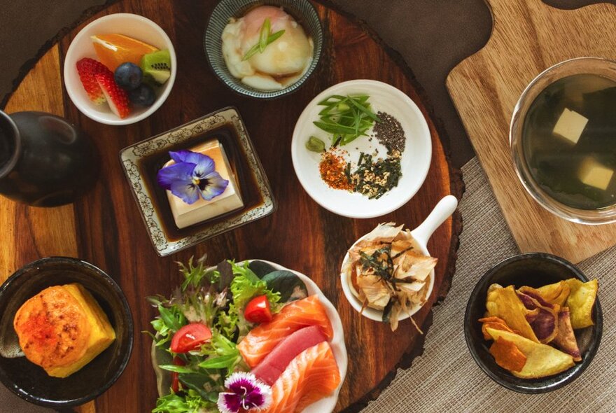 Overhead view of dishes on a restaurant table, including salmon, soup and salads.