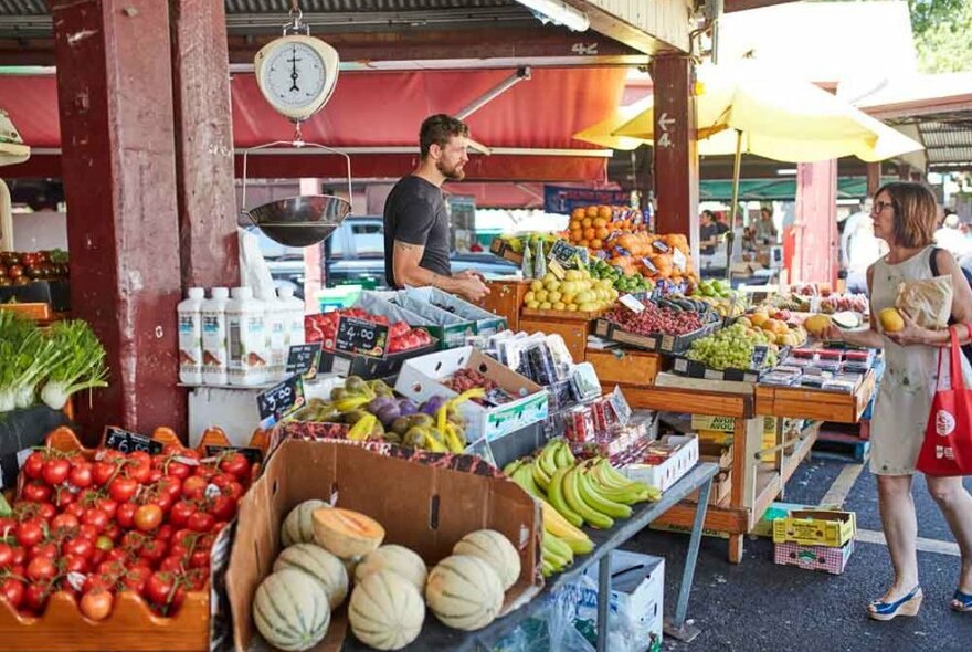 A woman buying fruit from a market stand