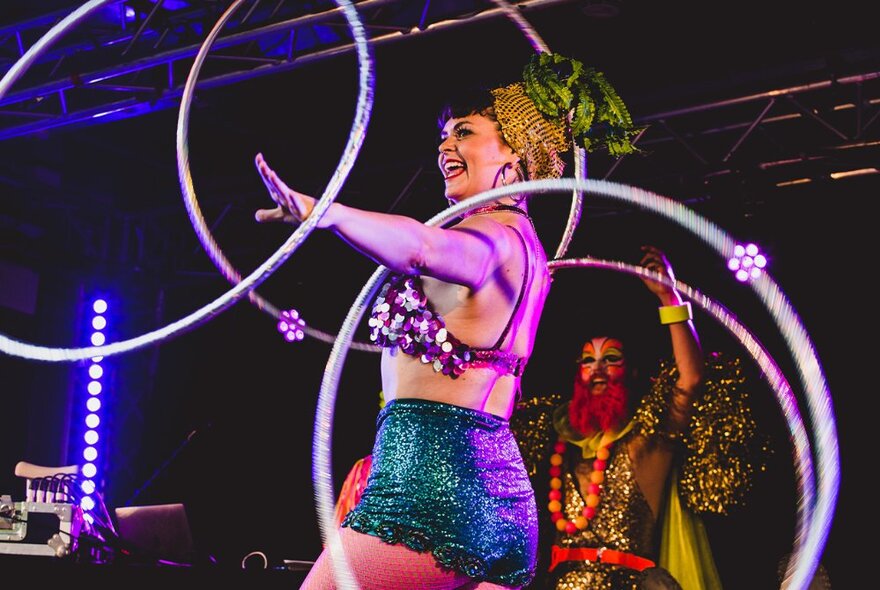 Nighttime, with a performer on stage twirling hula hoops in her arms.