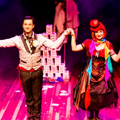 Two performers wearing bright costumes on a stage.