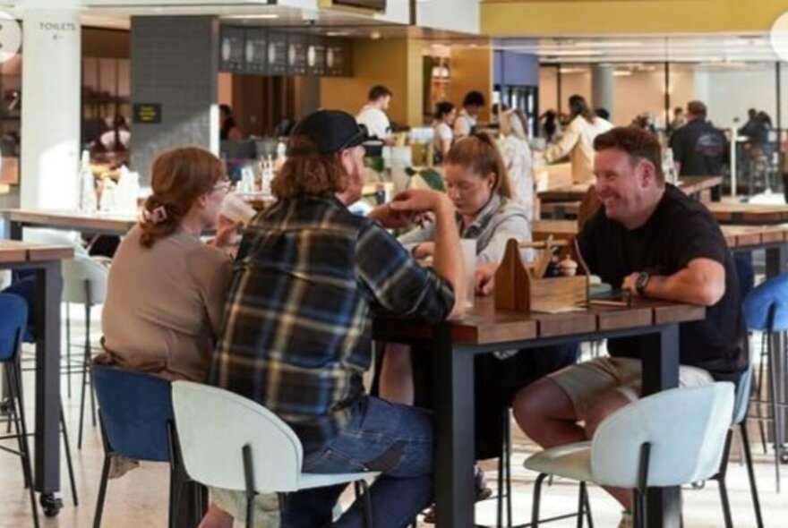 People enjoying a meal at a high table inside a large dining hall at St Andrews Beach Brewery at Melbourne Park.