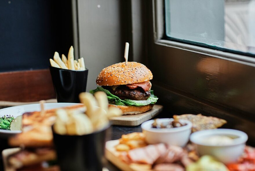 Table filled with plates of food including a classic pub burger, chips, and an antipasto grazing platter.