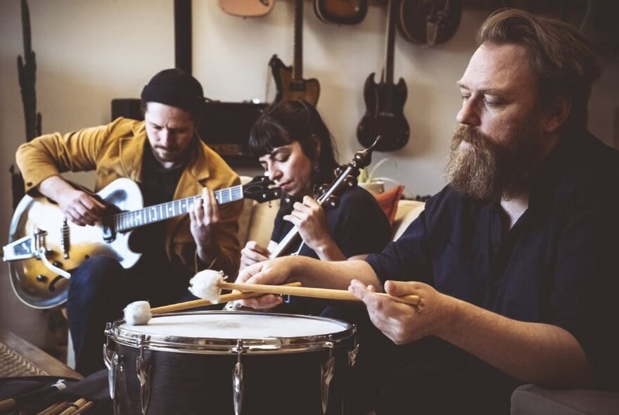 A Persian percussionist playing a drum, two musicians playing guitar and lute behind him.