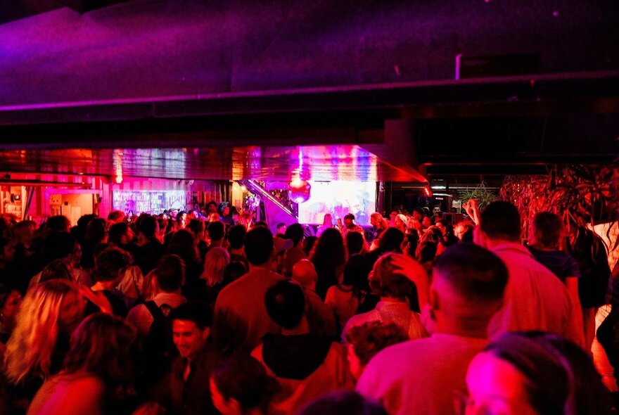 Red-lit dance crowd on a crowded dance floor.