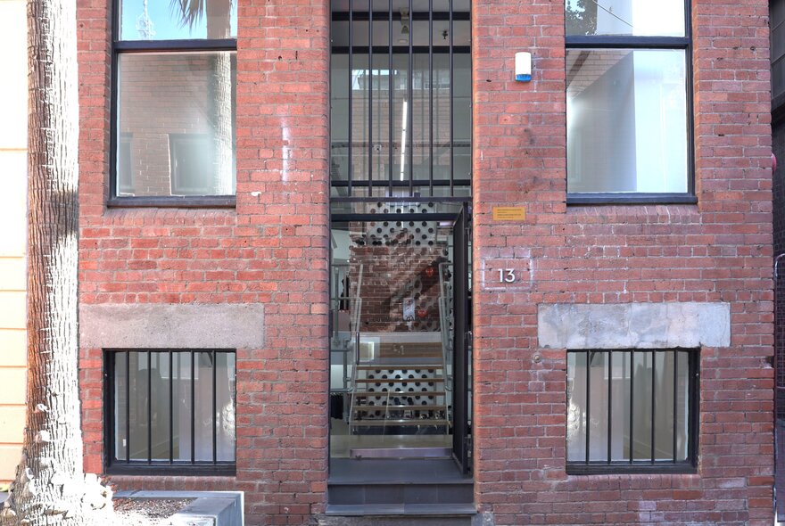 The entrance to a high-end clothing boutique with red brick facade and bars on the windows.