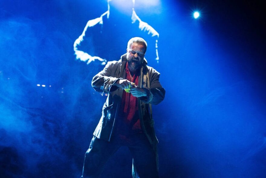 A solo male performer singing on stage in the musical Les Misérables The Arena Spectacular.