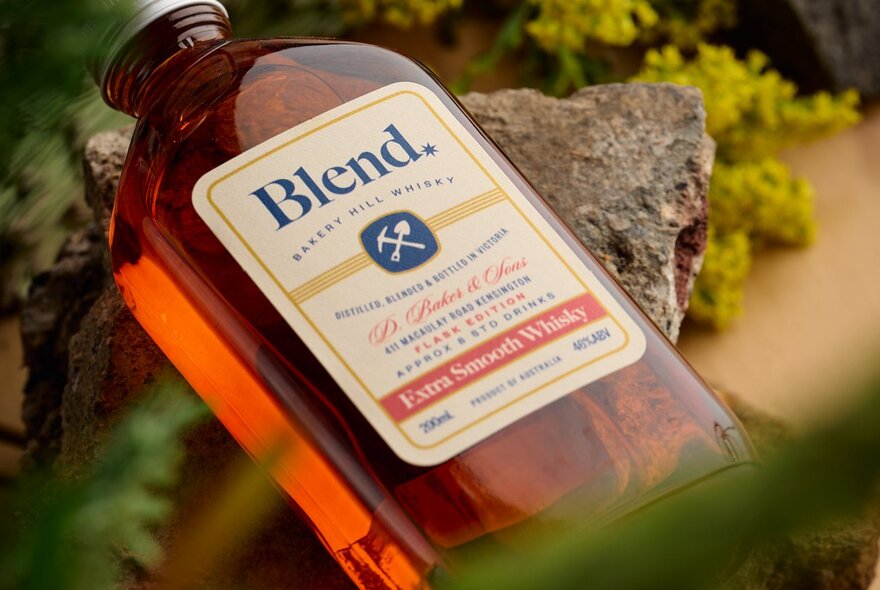 A labelled bottle of blended whiskey, displayed outdoors.