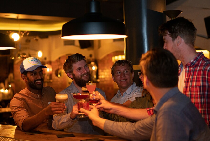 A group of men clinking glasses in a dimly lit pub.