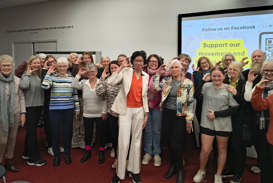 A group of smiling people posing in a room for a photo at a book talk.