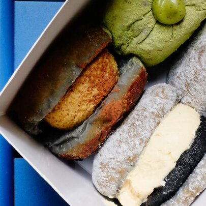Looking into a box containing four different kinds of filled donuts.