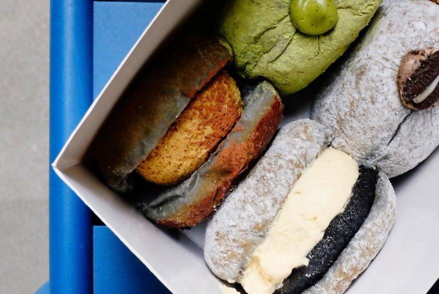 Looking into a box containing four different kinds of filled donuts.