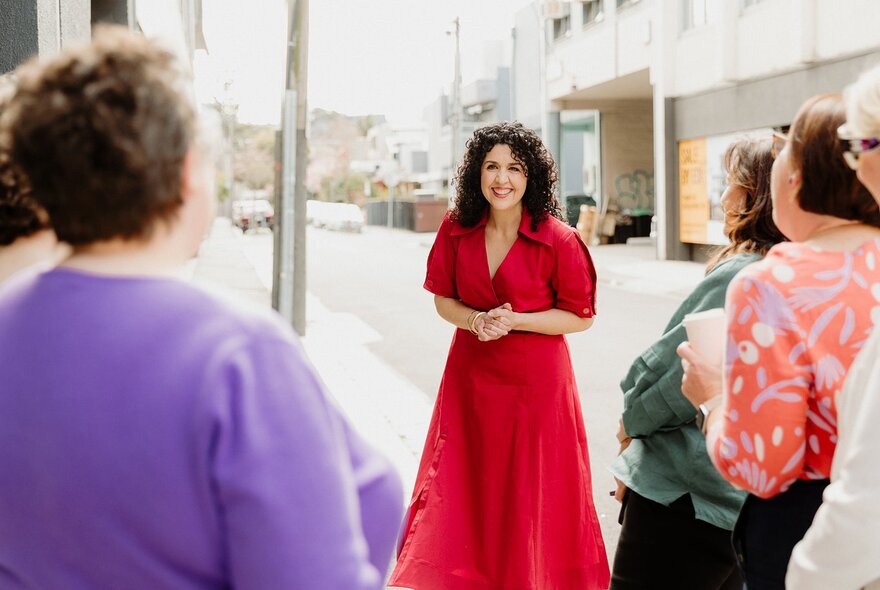 A tour guide in a red dress hosting a walking tour through city streets.