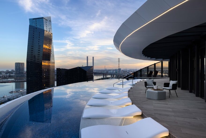 The curved, wet-edge resort-style rooftop infinity pool at the Melbourne Marriott Hotel, overlooking tall city buildings and the Bolte Bridge.