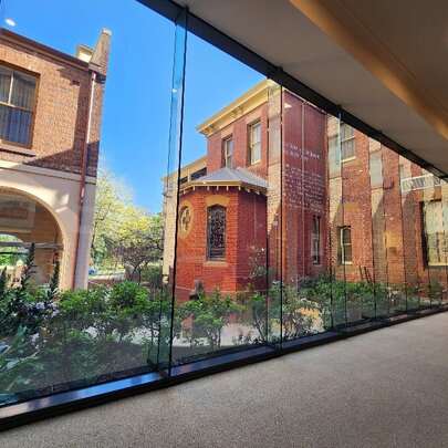 Looking out through floor to ceiling glass windows onto buildings around a courtyard, part of the Mary MacKillop Heritage Centre.