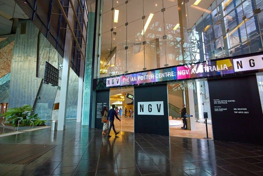 Two people walking through the doors to the Ian Potter Centre at the NGV.