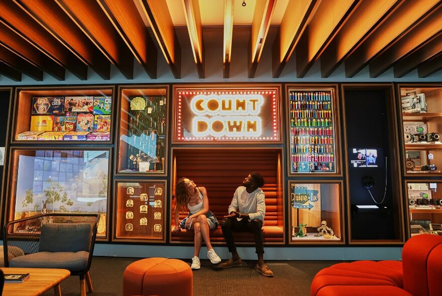 A couple in a gallery looking up at a sign that says count down.