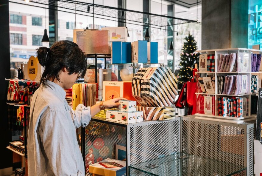 The back of a person in a museum shop browsing the displays. 