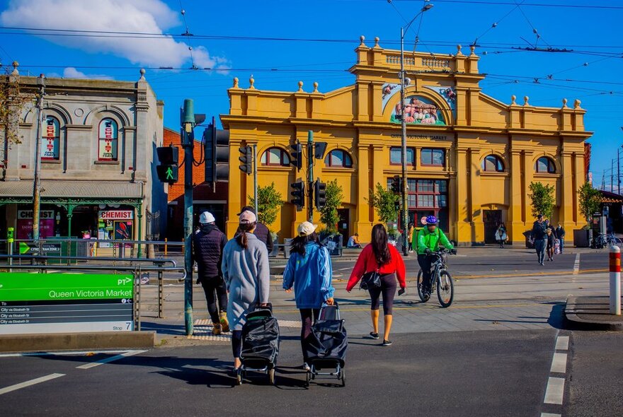 People are walking into a market with trolleys.