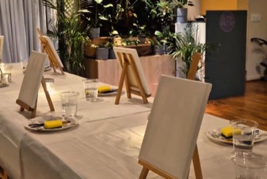 A table set with small easels and plates of paint pots. 