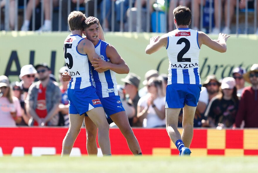 North Melbourne AFL football players on the field during a match.
