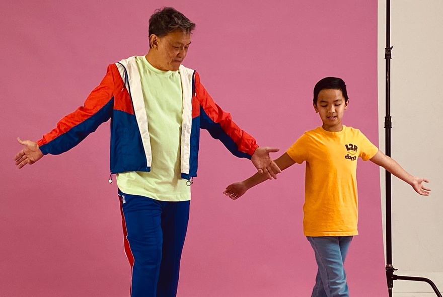 Adult and child standing with arms oustretched.