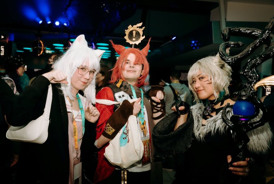 Three people dressed in cosplay, smiling and posing for the camera.