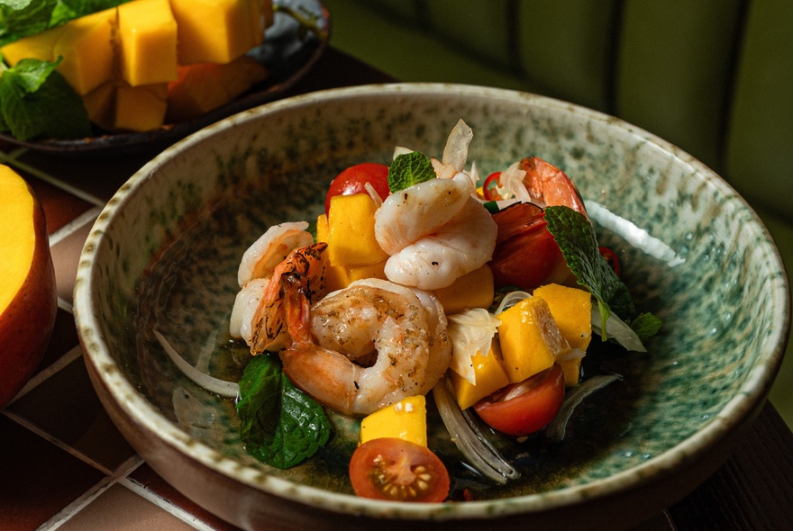 A Thai prawn dish with brightly coloured vegetables, in a mottled green bowl.