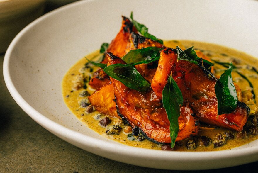A plate of red fish in a yellow sauce with garnish.