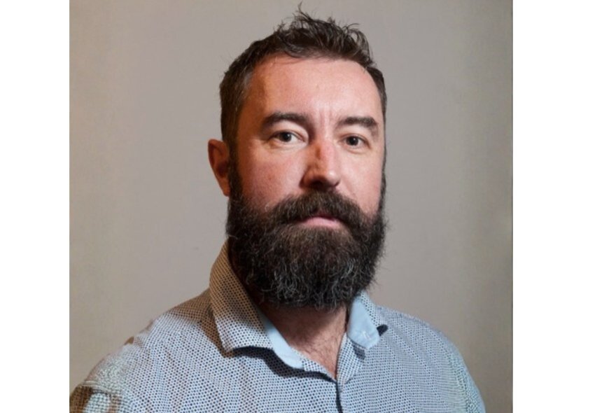Tim Byrne, with beard and wearing a blue shirt.