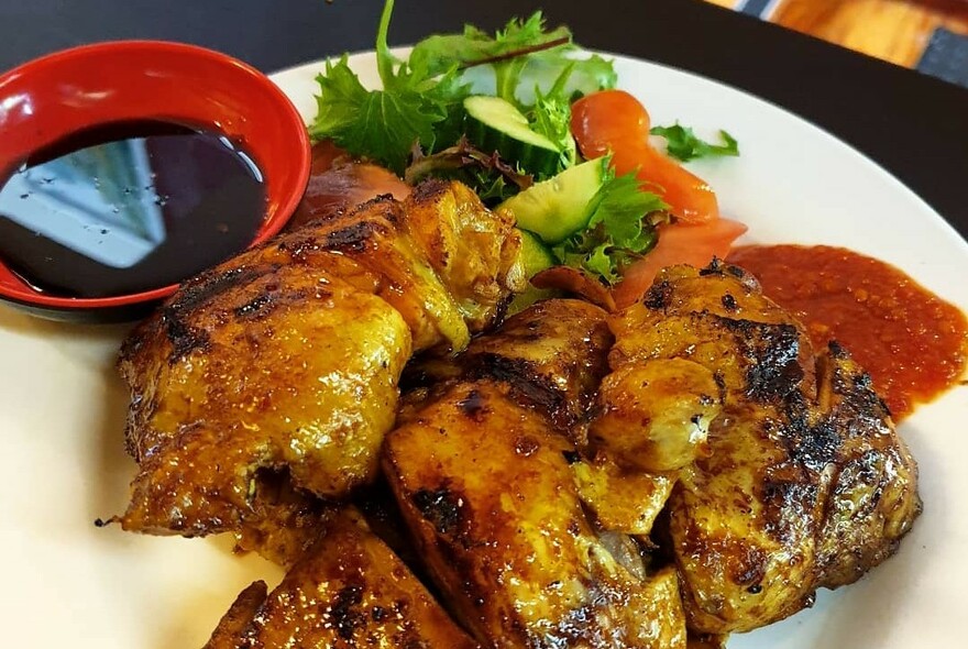 Plate with meat satays and bowl of sauce on the side.