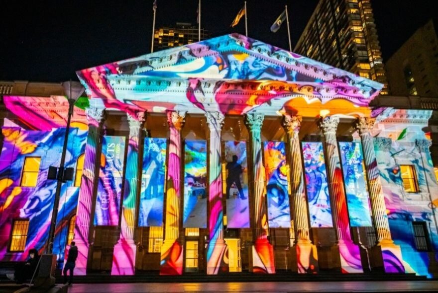 Melbourne Town Hall lit up in psychedelic colours at night.
