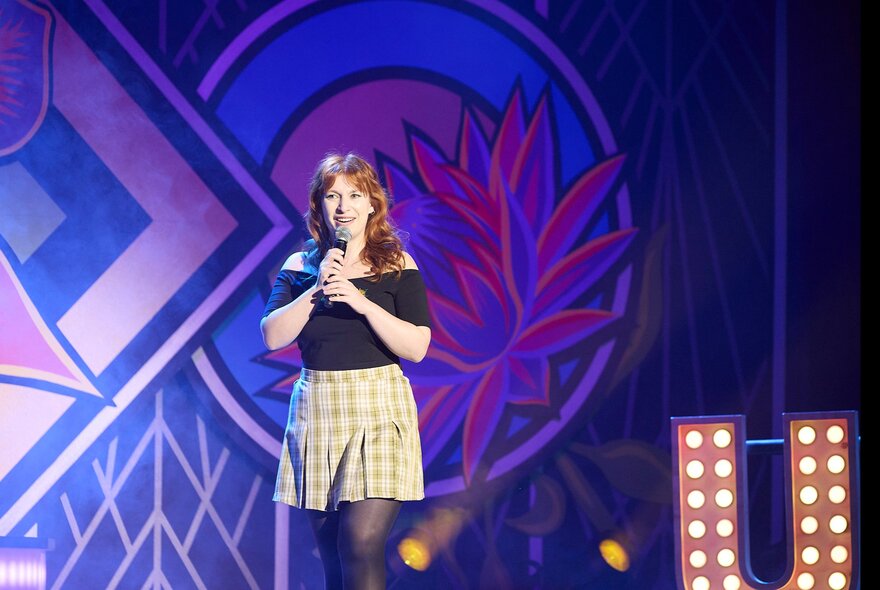 Performer Robyn Reynolds on stage, holding a microphone in her hands.