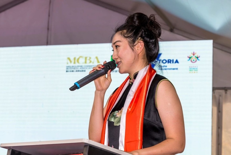 Person wearing a red scarf speaking into a microphone.
